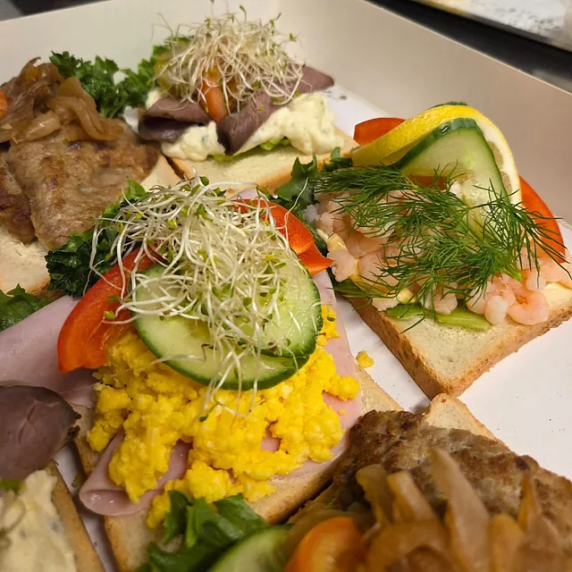 Variasjon av snitter og med fargerik topping, inkludert spirer og potetsalat.