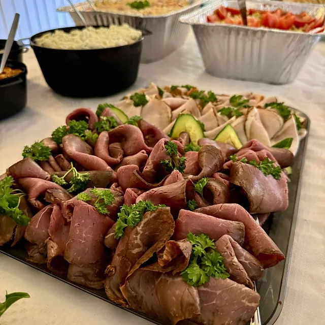 Snitter med roastbiff rullet og pyntet med salat og stekt løk, servert på fat.