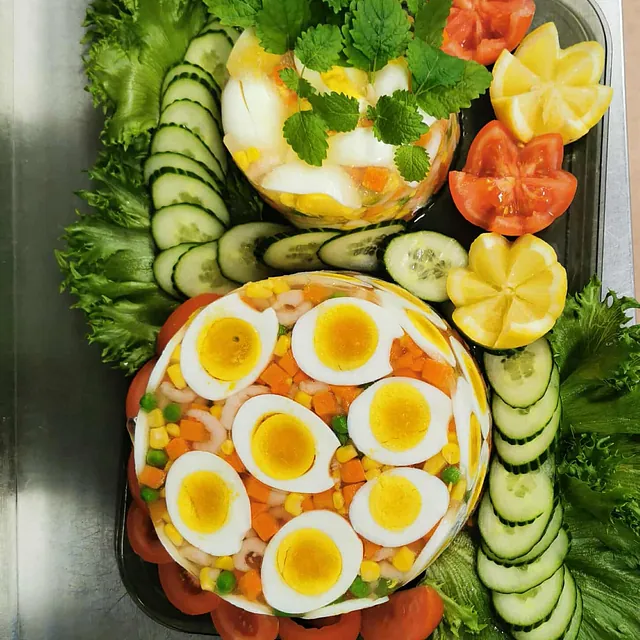 Kabaret sett ovenfra, dekorert med egg, agurk, sitron og grønt på et metallbrett.
